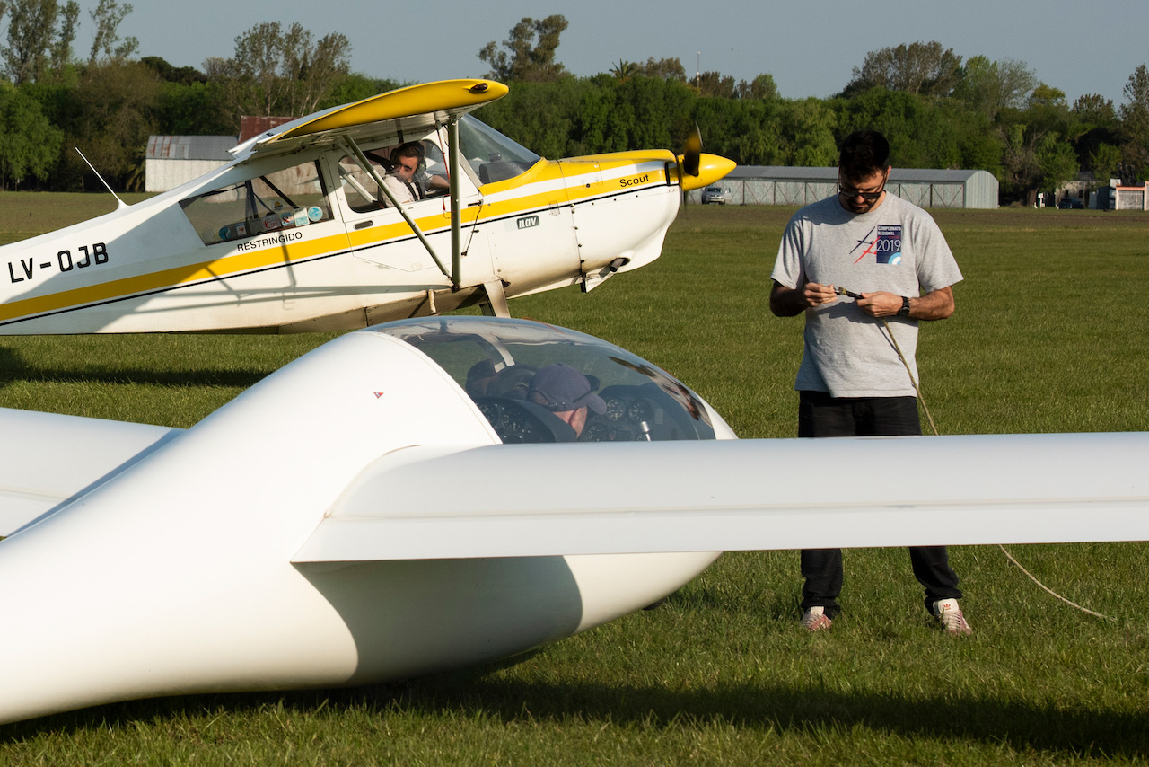 Alumno junto a un planeador biplaza, con el avión remolcador detrás