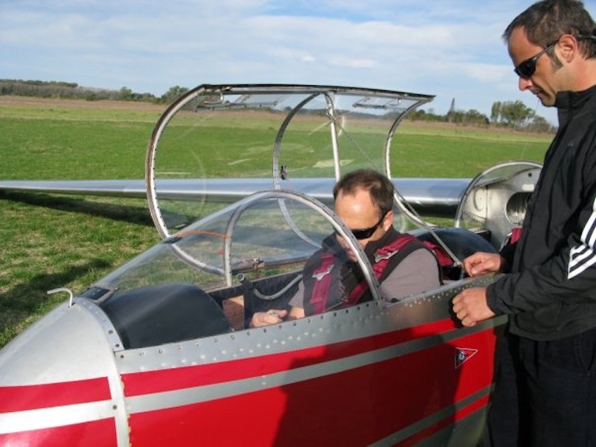 Instructor ajustando el arnés de un pasajero en la cabina del planeador